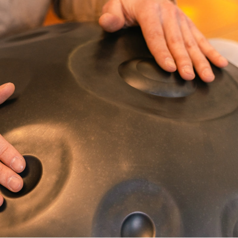 A beginner learning to play a handpan instrument in a serene setting.