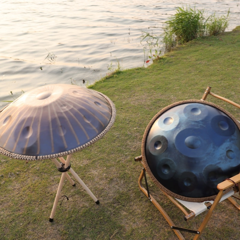 Two beautifully designed Cosmoshandpan handpans placed by a tranquil lakeside for sound meditation.