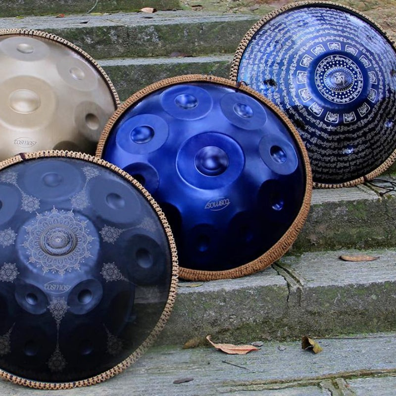 Different styles of handpans showcased on stone stairs in a peaceful park setting.