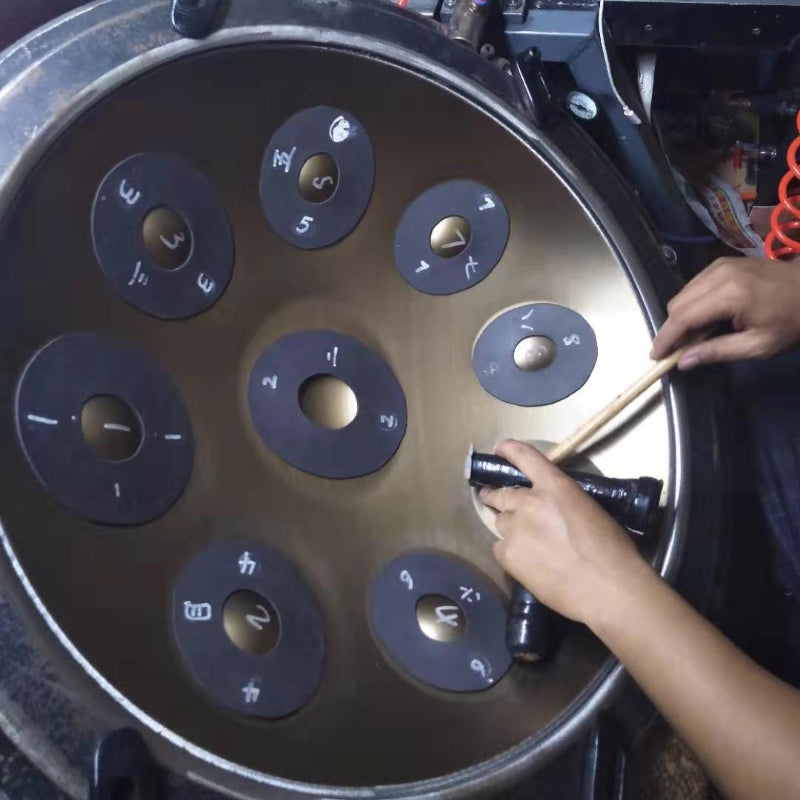 Craftsman carefully tuning a handpan drum by hand in a workshop to ensure precise pitch and rich, harmonious sound quality.