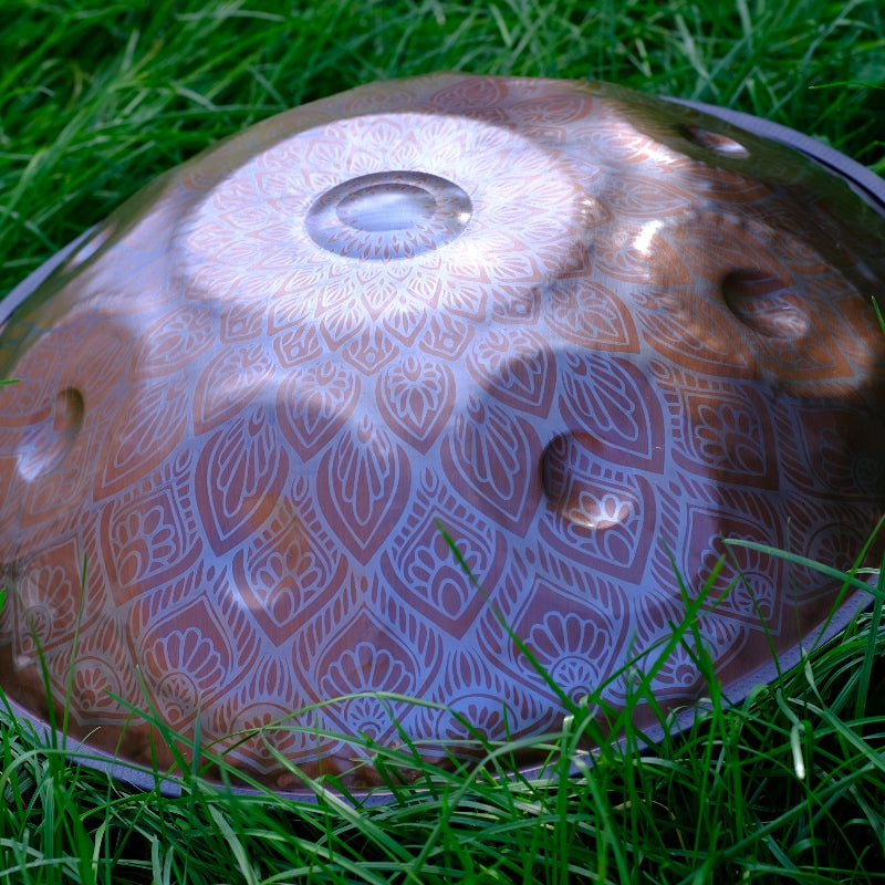 There is a patterned brightly colored handpan on the grass.
