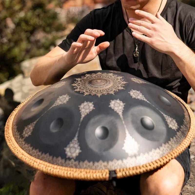 Artist creating music with a black patterned handpan